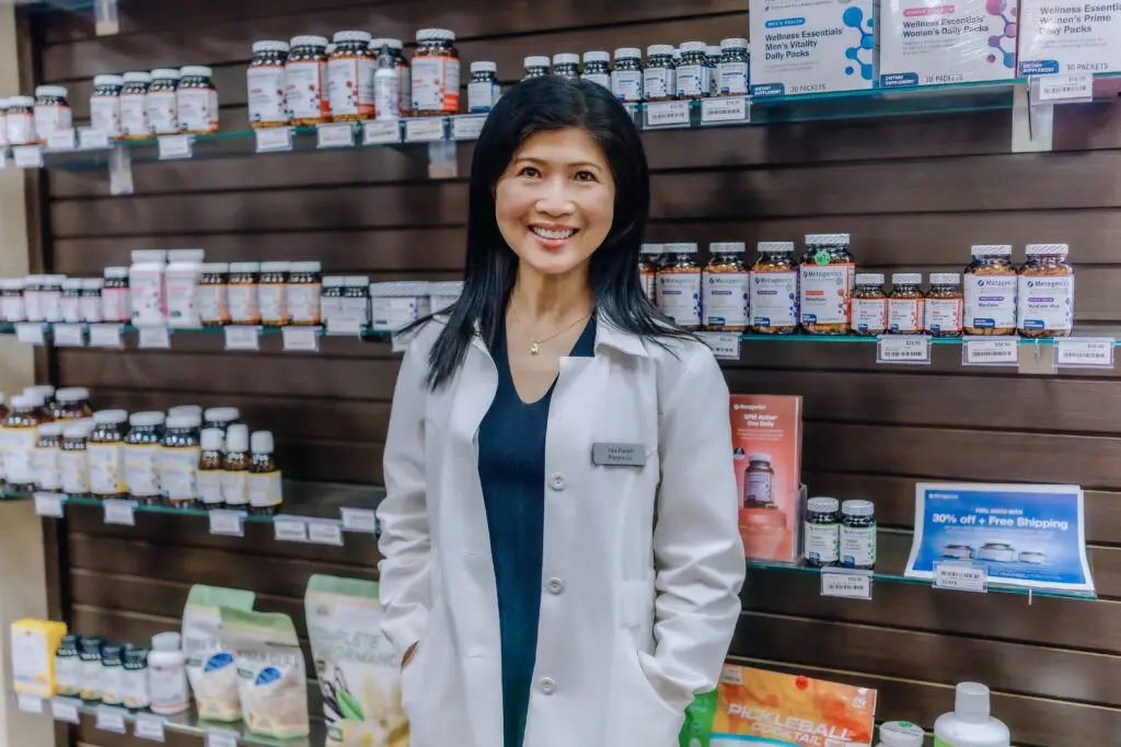 Tina Huynh, RPh, ABAAHP standing in front of supplements at Allen Family Drug