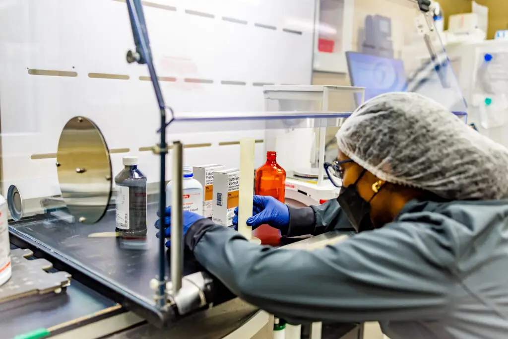 person compounding medications within a hood