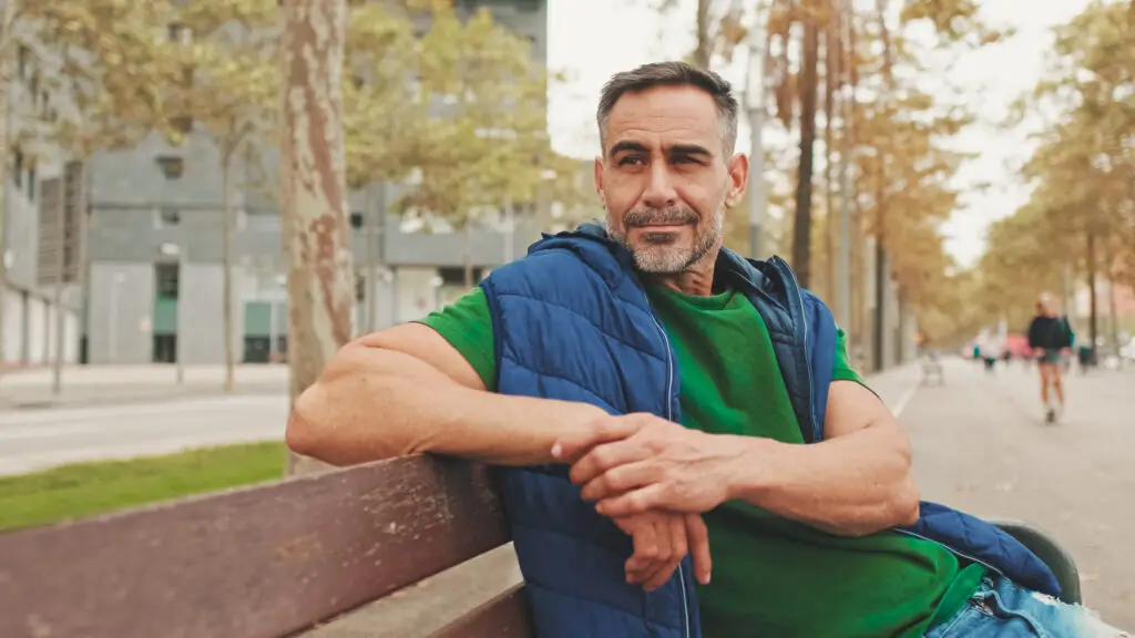 Mature man casually sitting on a bench in the park