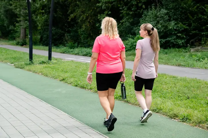 two woman going for a walk outside on a trail